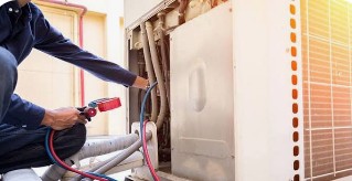 Albos HVAC technician servicing a residential outdoor condenser unit with gauges